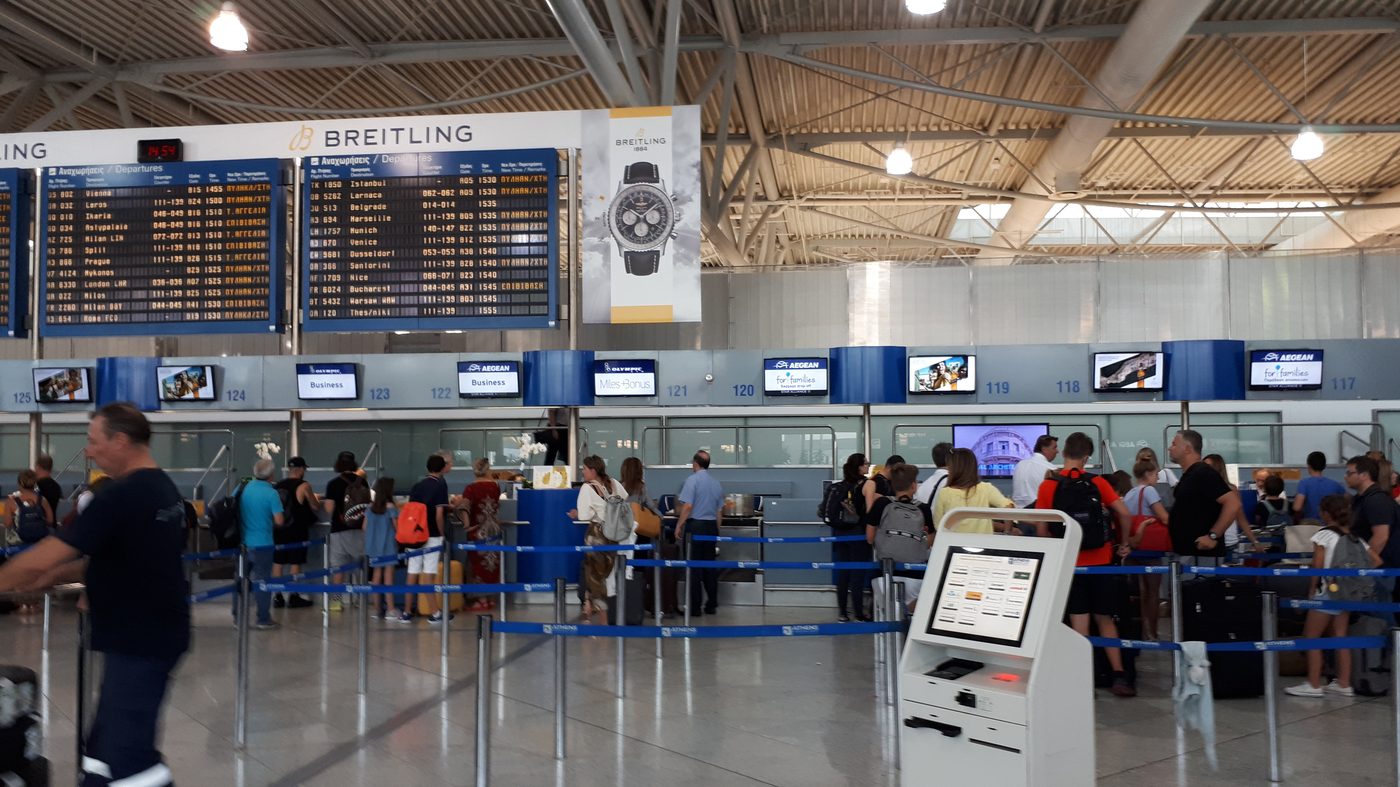Check-in hall at Athens International Airport with departure boards and passengers