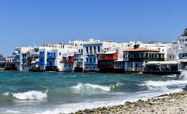 The colorful waterfront buildings of Little Venice in Mykonos with balconies overlooking the turquoise Aegean Sea