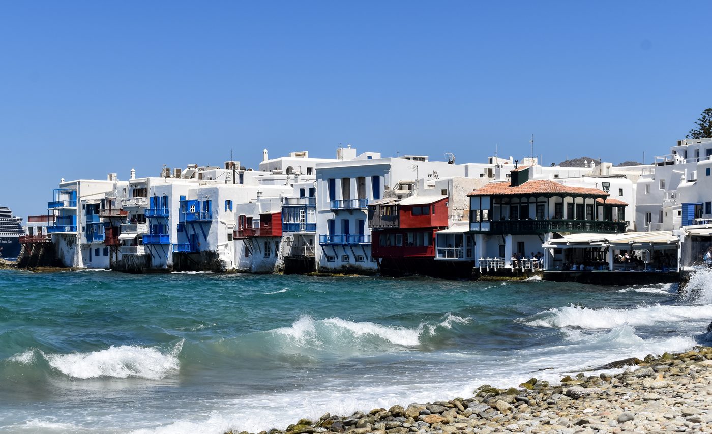 The colorful waterfront buildings of Little Venice in Mykonos with balconies overlooking the turquoise Aegean Sea
