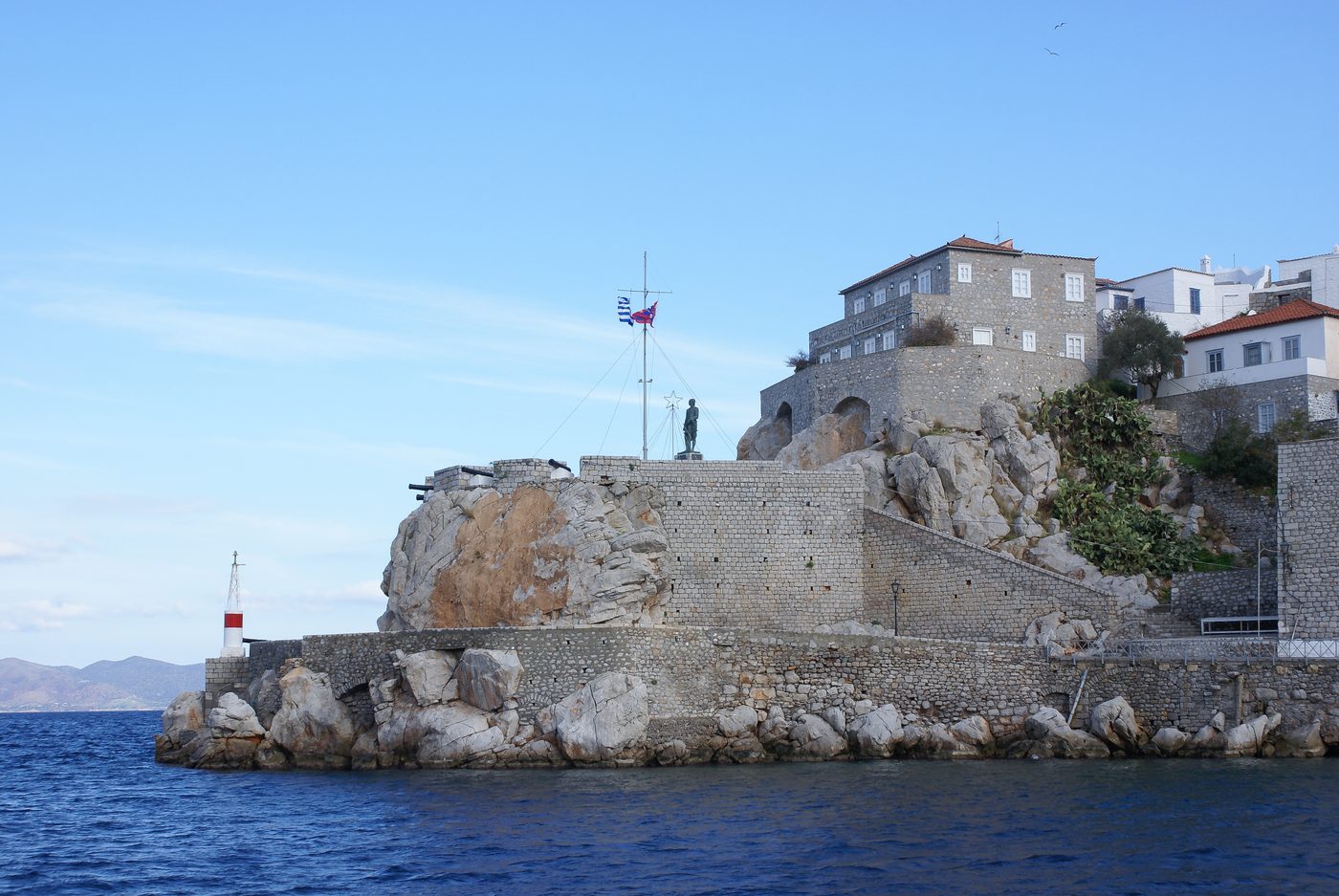 Hydra harbour town with stone mansions rising from the waterfront and boats moored in the bay