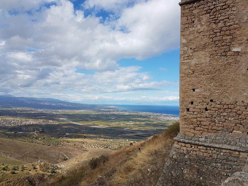 A stone corner tower of the Acrocorinth fortress overlooking the plain of Corinth and the sea