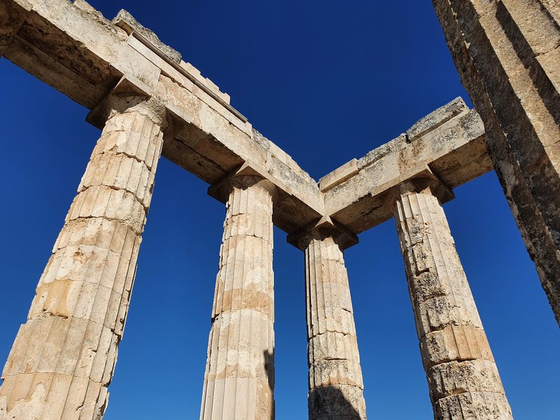 Looking up at the fluted Doric columns of the Temple of Zeus at Nemea against a clear sky