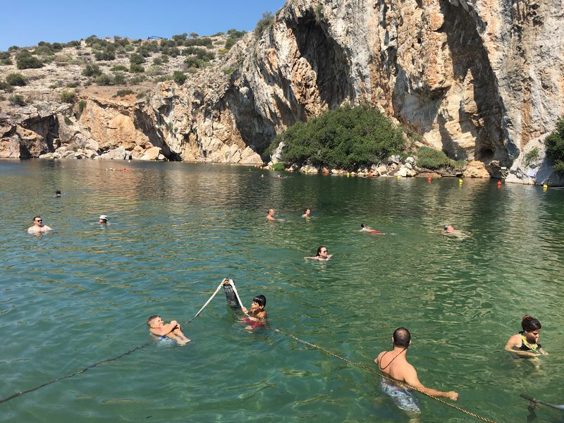 Lake Vouliagmeni thermal lake near Athens with swimmers in mineral-rich turquoise water surrounded by cliffs