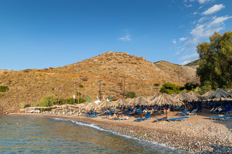 Vlychos Beach on Hydra island Greece with crystal-clear turquoise water and a pebbly shoreline surrounded by hills