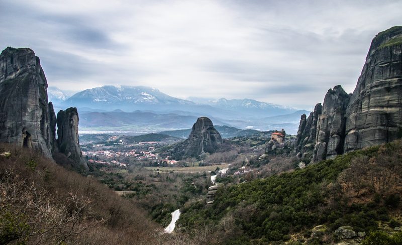 Meteora monasteries perched on towering sandstone rock pillars rising above a green valley in Thessaly, Greece