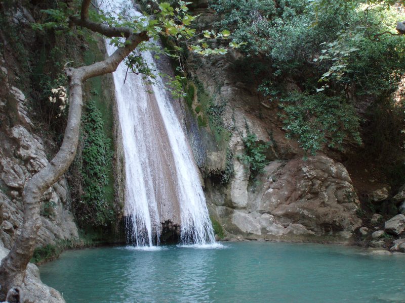 Waterfall cascading into a turquoise natural pool on the Neda River in the Peloponnese, Greece