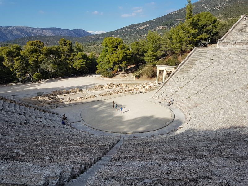 The circular orchestra of the Epidaurus theatre, with the ruined stage building visible behind it