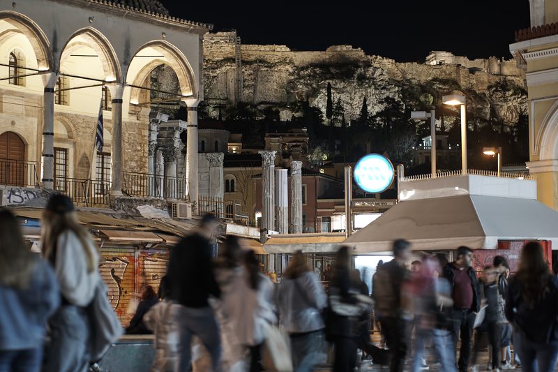 Monastiraki Square in Athens illuminated at night with people walking around