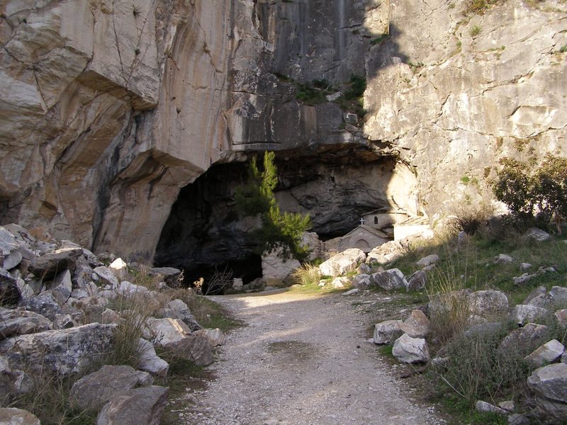 The wide rocky entrance of Ntavelis Cave on Mount Penteli, showing the cave mouth framed by rough stone walls