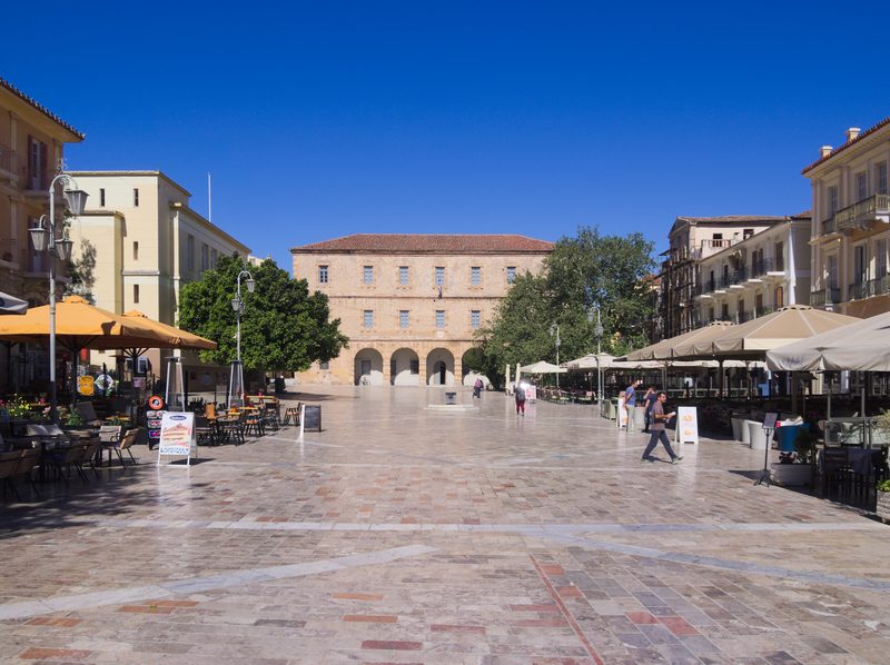 Syntagma Square in Nafplio old town, a wide public square lined with neoclassical buildings and the Venetian arsenal at the far end