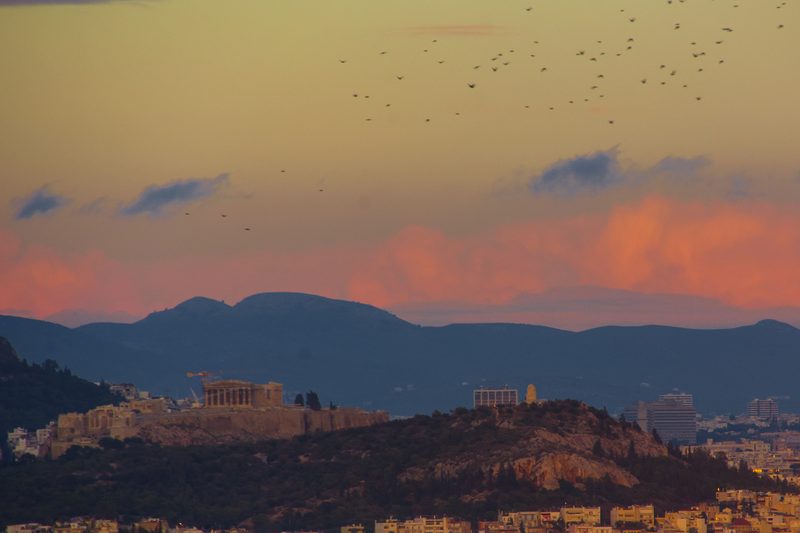 Athens sunset panorama with the Acropolis and Filopappou Hill silhouetted against a warm golden sky