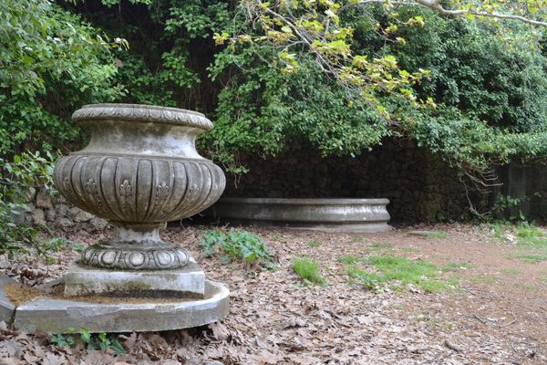 Stone stairway descending through the lush former royal garden at Tatoi estate with mature trees and a reflecting pool
